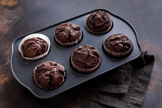 Alto ángulo de bandeja con muffins de chocolate y tela.