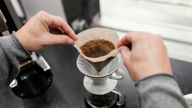 Alto ángulo de barista masculino despegando el filtro de café