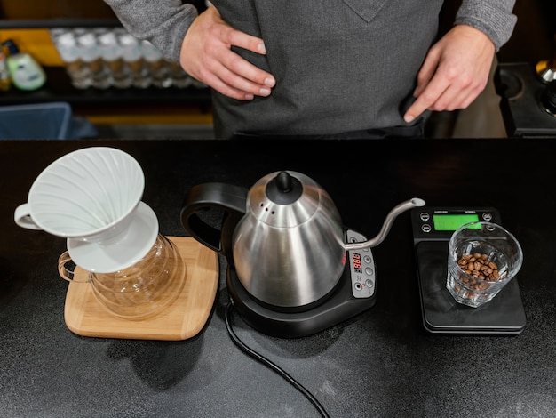 Alto ángulo de barista masculino preparando café con hervidor y filtro