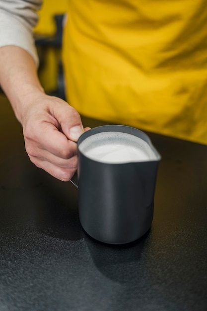 Alto ángulo de barista sosteniendo la taza de leche