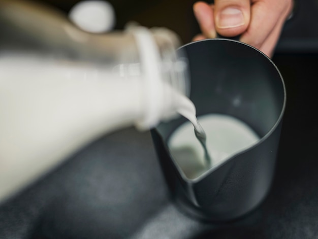 Alto ángulo de barista vertiendo leche