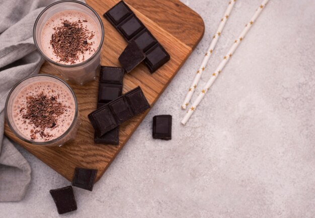 Alto ángulo de batidos de chocolate con pajitas y espacio de copia