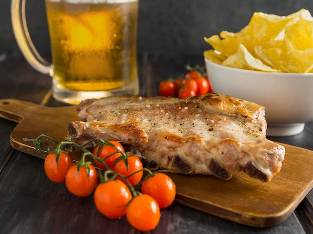 Alto ángulo de bistec con cerveza y tomates