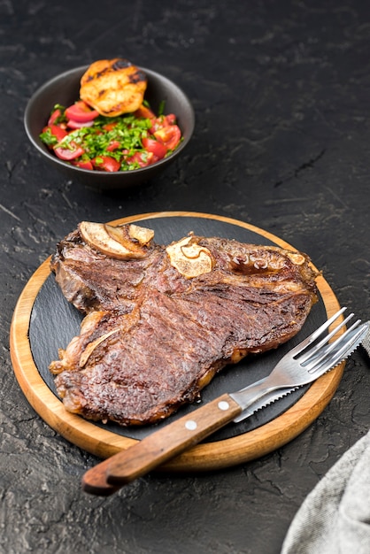 Alto ángulo de bistec con cubiertos y ensalada