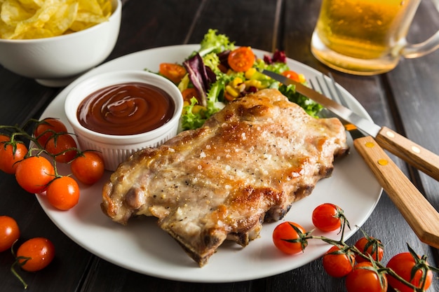 Alto ángulo de bistec en plato con cerveza y ensalada