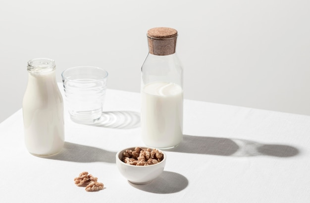 Alto ángulo de botella de leche con vaso vacío y tazón de nueces