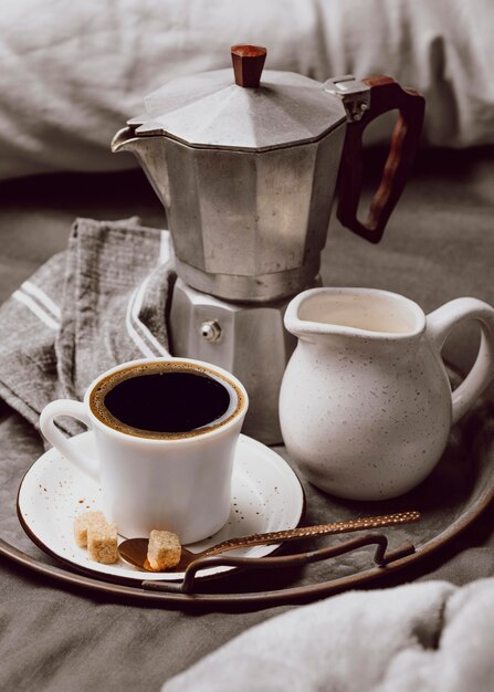 Alto ángulo de café de la mañana en la cama con leche y hervidor