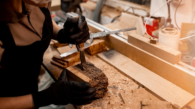 Alto ángulo de carpintero femenino en el estudio con herramientas para esculpir madera