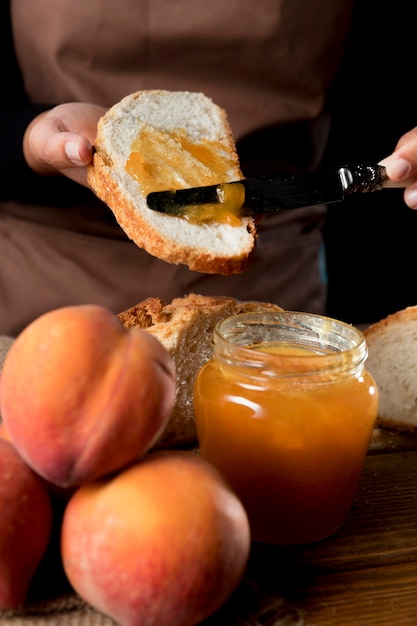 Foto gratuita alto ángulo del chef extendiendo gelatina de durazno sobre pan