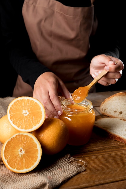 Alto ángulo de chef con frasco de mermelada de naranja