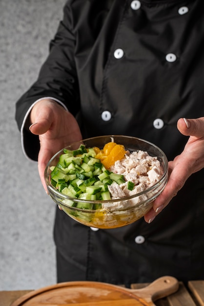 Alto ángulo de chef mujer sosteniendo tazón con ingredientes