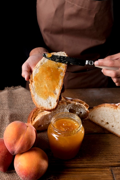 Alto ángulo del chef untando mermelada de durazno en pan