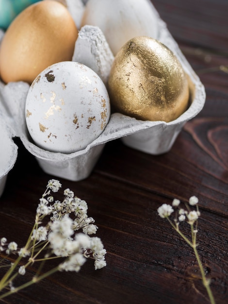 Foto gratuita alto ángulo de coloridos huevos de pascua en cartón con gypsophila planta