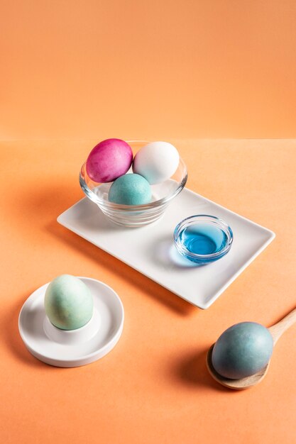 Alto ángulo de coloridos huevos de pascua pintados en un plato con tinte y cuchara