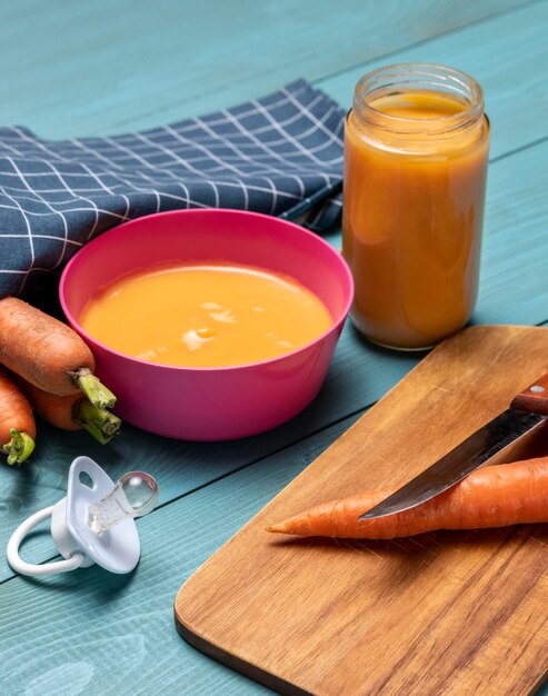 Alto ángulo de comida para bebés en un tazón con chupete y zanahorias