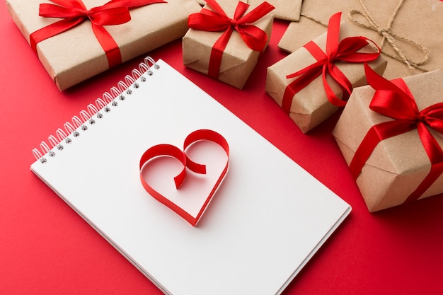 Alto ángulo de cuaderno con forma de corazón de papel y regalos