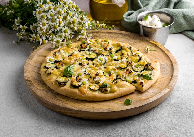 Alto ángulo de deliciosa pizza cocida con flores de manzanilla