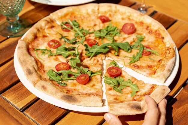 Alto ángulo de deliciosa pizza con rúcula y tomates cherry
