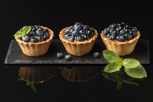 Alto ángulo de deliciosas tartas de arándanos en pizarra con menta