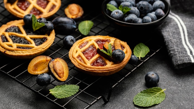 Alto ángulo de deliciosas tartas con ciruelas en rejilla de enfriamiento