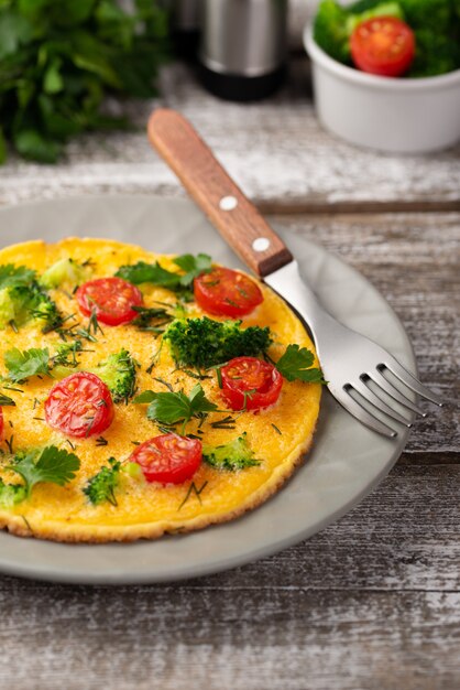 Alto ángulo de desayuno tortilla en plato con tenedor y hierbas