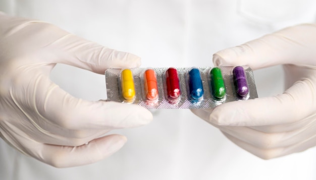 Alto ángulo del doctor con pastillas de colores del arco iris en papel de aluminio