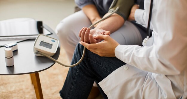 Alto ángulo de la doctora del centro de recuperación covid que controla la presión arterial del paciente anciano