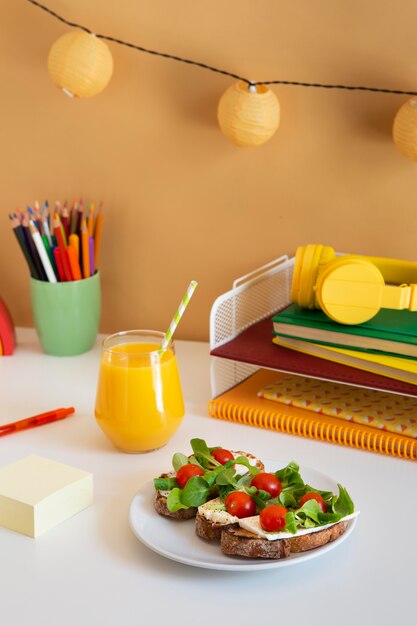 Alto ángulo de escritorio para niños con bocadillos y jugo de naranja