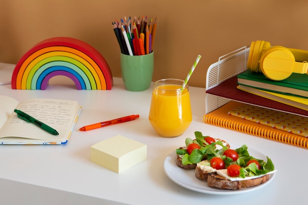 Alto ángulo de escritorio para niños con bocadillos y jugo de naranja