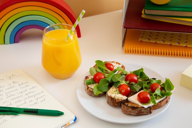 Alto ángulo de escritorio para niños con bocadillos y jugo de naranja