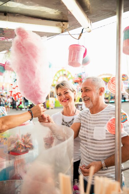 Alto ángulo feliz pareja comprando algodón de azúcar