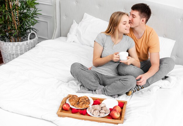 Alto ángulo feliz pareja con desayuno en la cama