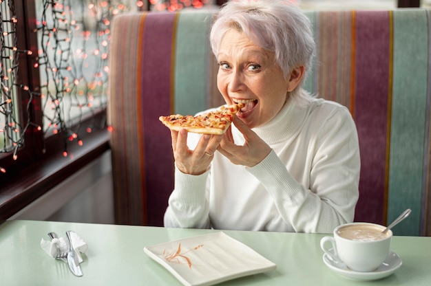 Alto ángulo femenino senior en el restaurante comiendo