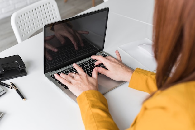 Alto ángulo femenino trabajando en la computadora portátil