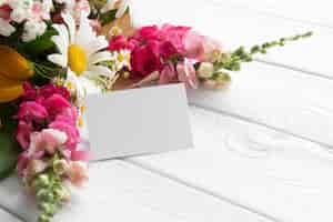 Foto gratuita alto ángulo de flores con tarjeta en blanco