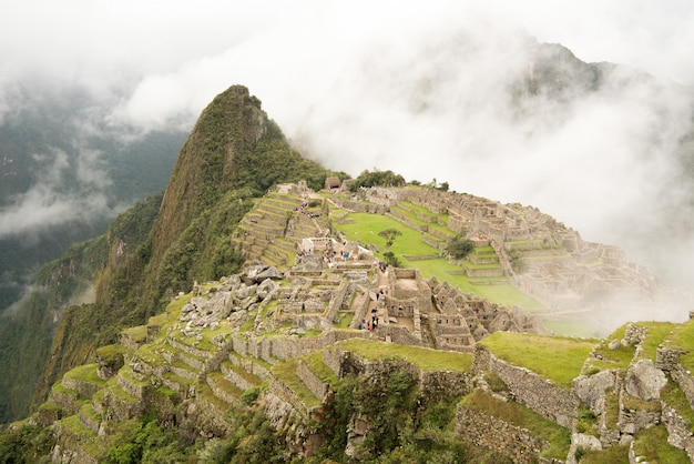 Alto ángulo de la hermosa ciudadela de Machu Picchu, rodeado de montañas de niebla en Urubamba, Perú