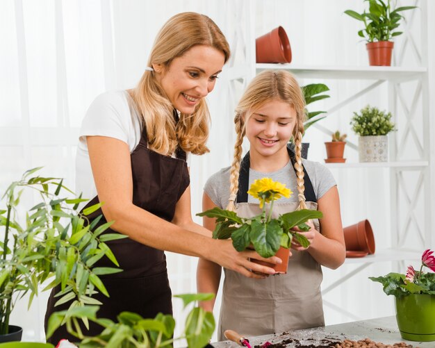 Alto ángulo hija y madre plantando flores