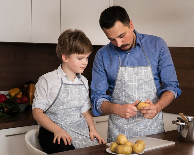 Alto ángulo hijo y papá limpiando papas