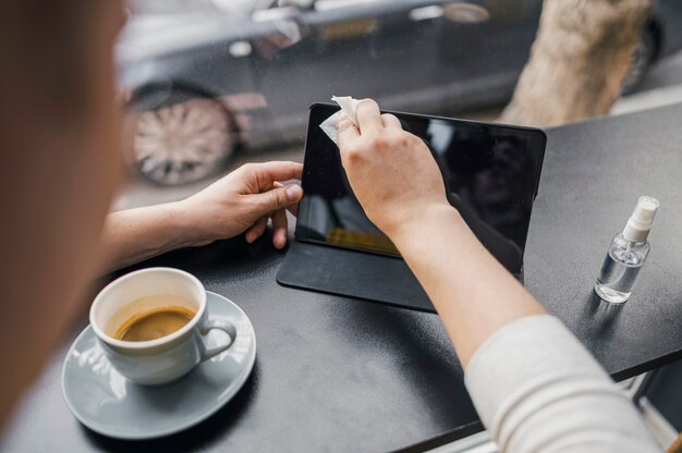 Alto ángulo del hombre disfrutando de una taza de café con tableta