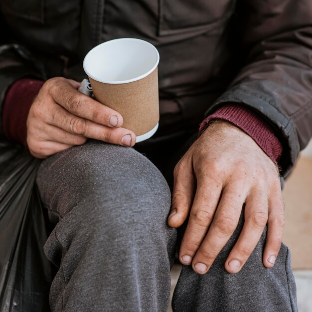 Foto gratuita alto ángulo de hombre sin hogar sosteniendo taza vacía