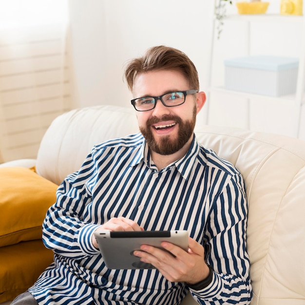 Alto ángulo de hombre sonriente en el sofá con tableta