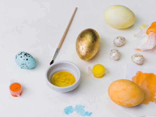 Foto gratuita alto ángulo de huevo de pascua dorado con tinte y pincel