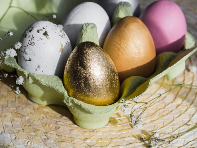 Alto ángulo de huevos de Pascua multicolores en cartón sobre mantel individual