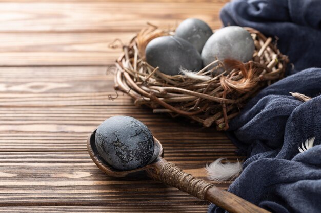 Alto ángulo de huevos de Pascua en nido de pájaro con cuchara de madera y textil