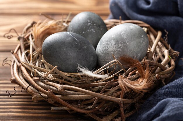 Alto ángulo de huevos de pascua en nido de pájaro con plumas y textiles