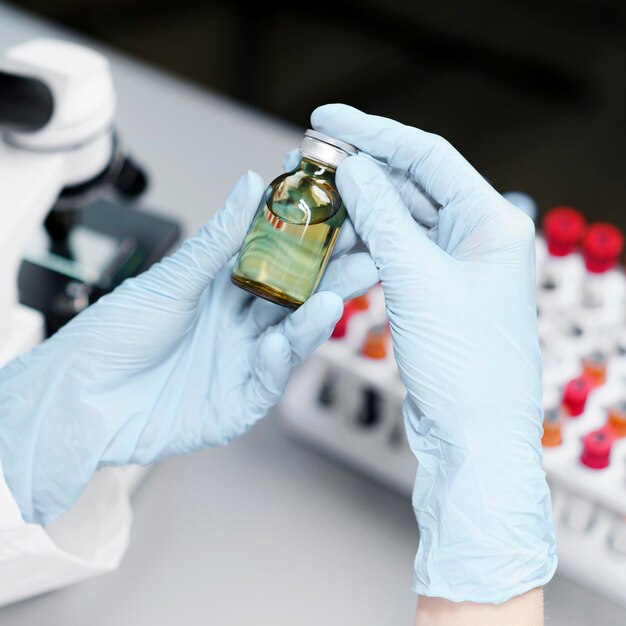 Alto ángulo de investigadora en el laboratorio con botella de vacuna