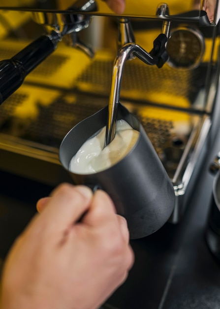 Alto ángulo de leche espumosa barista masculina