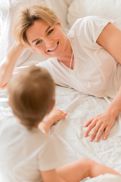 Alto ángulo madre y bebé jugando en la cama