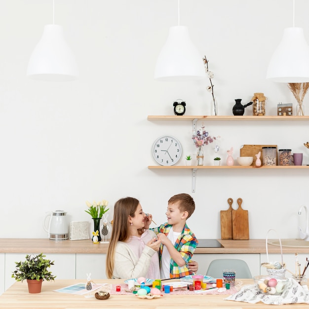 Alto ángulo madre e hijo pintando huevos