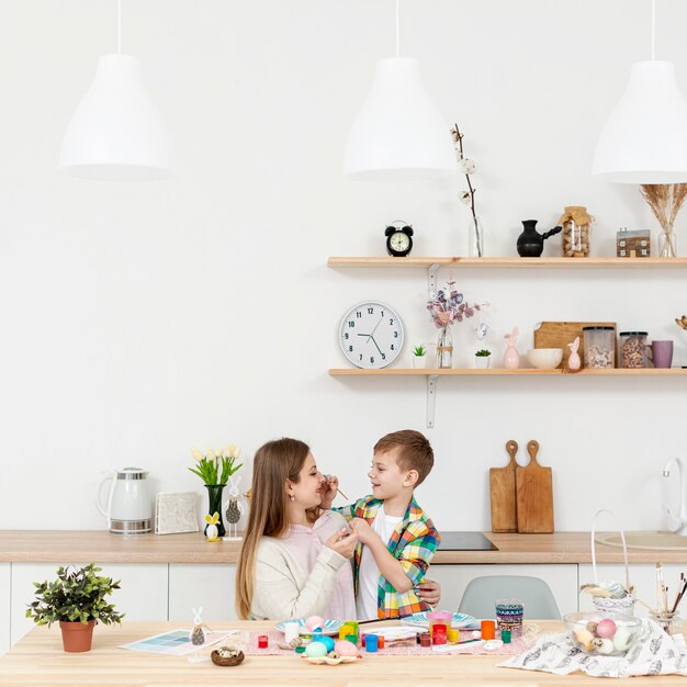 Alto ángulo madre e hijo pintando huevos